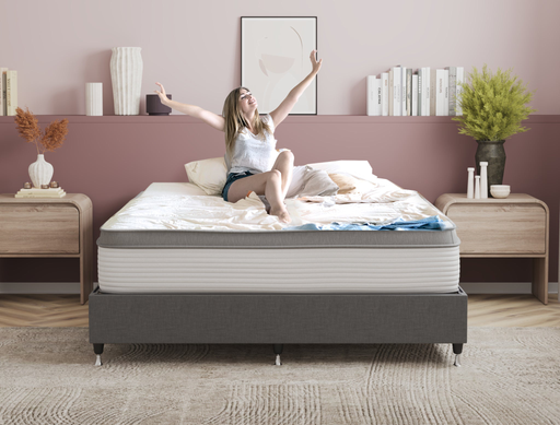 happy woman sitting on a king mattress on a bed frame in a bedroom