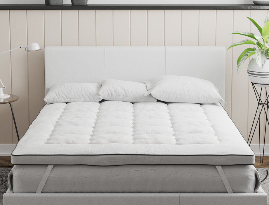 front view of a king mattress topper with three pillows on a bed frame in a bedroom